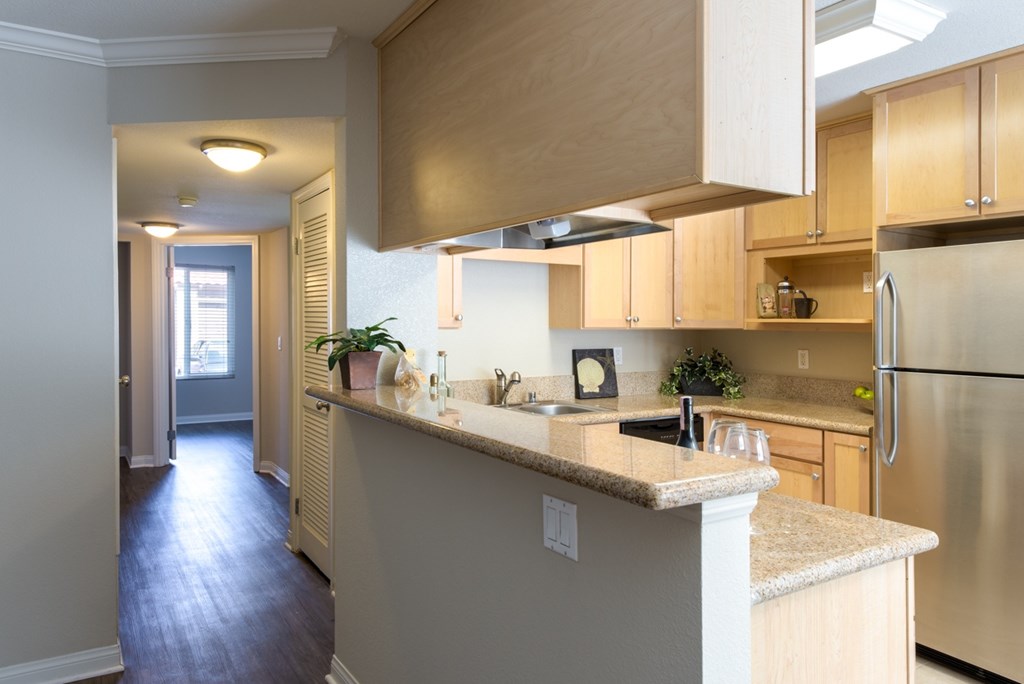 A kitchen with a refrigerator, sink, and cabinets.