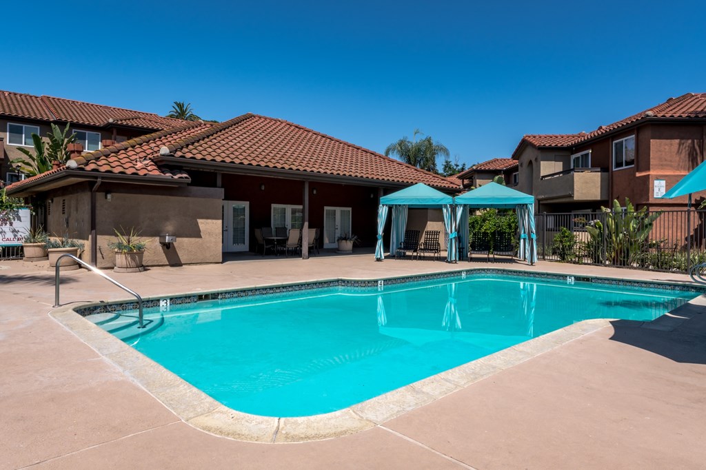 A swimming pool surrounded by a patio and umbrellas.