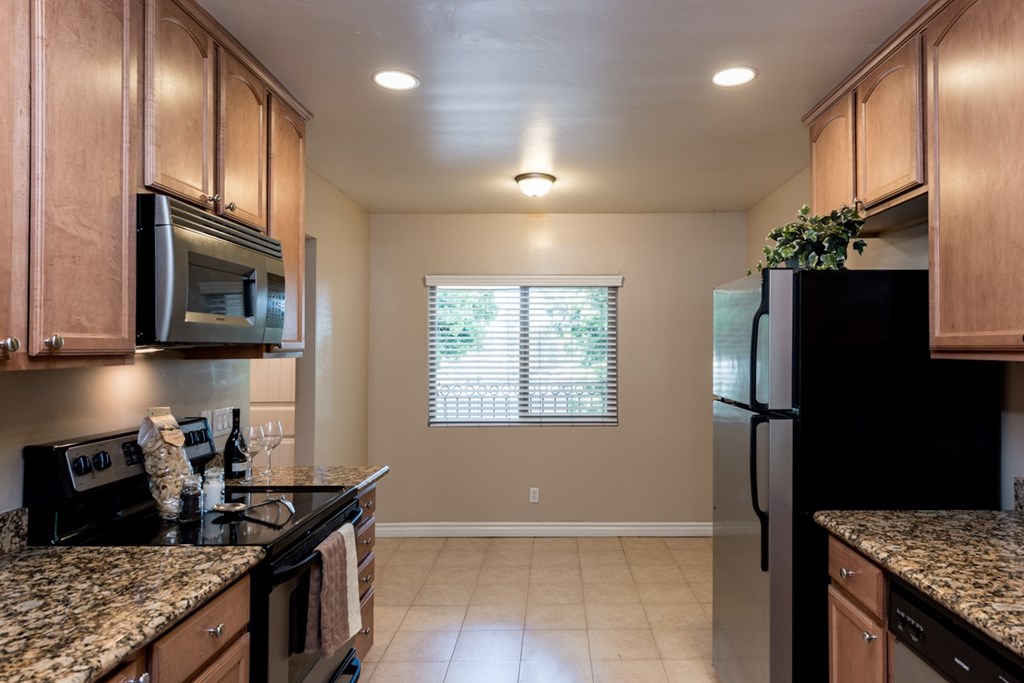 A kitchen with granite countertops and a black refrigerator.