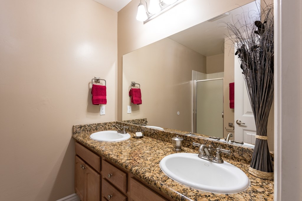 A bathroom with a granite countertop and two sinks.