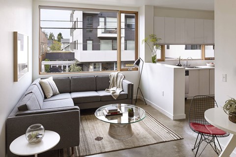 A modern living room with a grey couch and a glass coffee table.