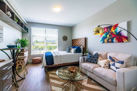 A living room with a white couch and a bed in the background.