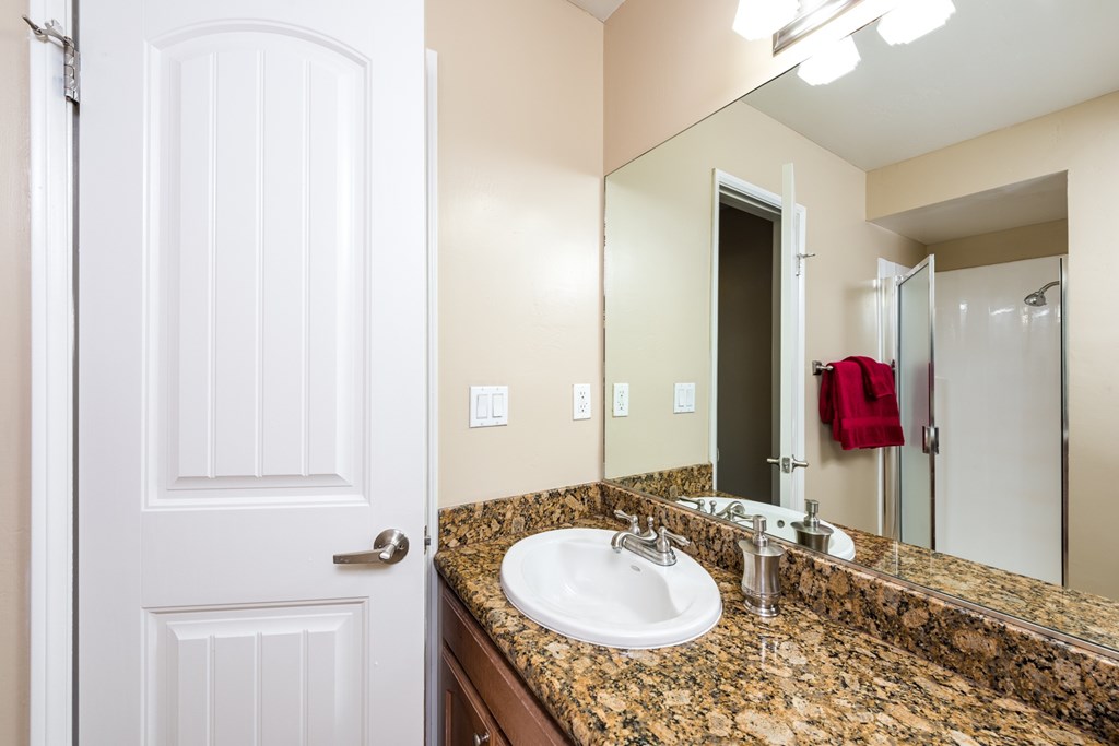 A bathroom with a granite counter top and a white sink.