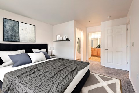 A bedroom with a large bed and a painting on the wall.