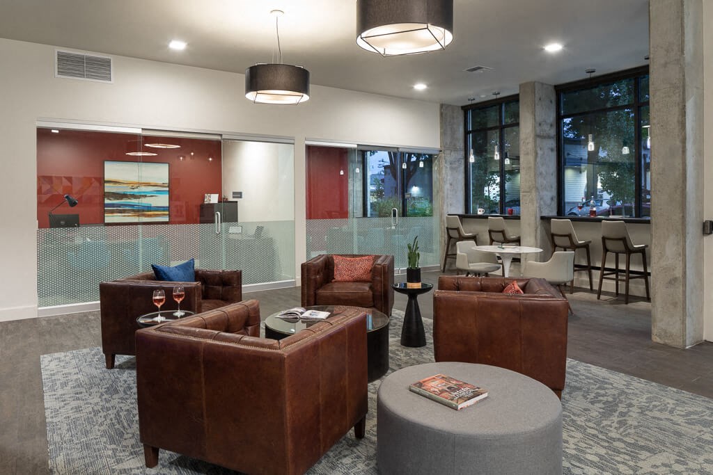 A modern living room with brown leather furniture and a grey ottoman. at Ravello Apartments, Washington
