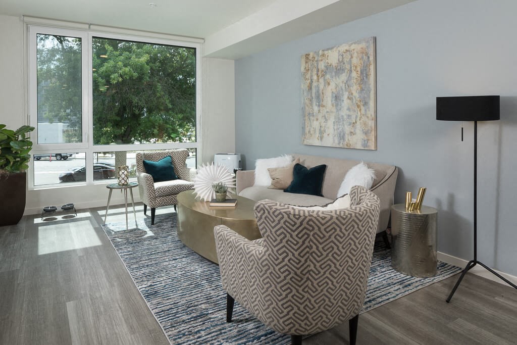 A living room with a patterned chair and a couch with a blue pillow. at Ravello Apartments, Washington, 98052