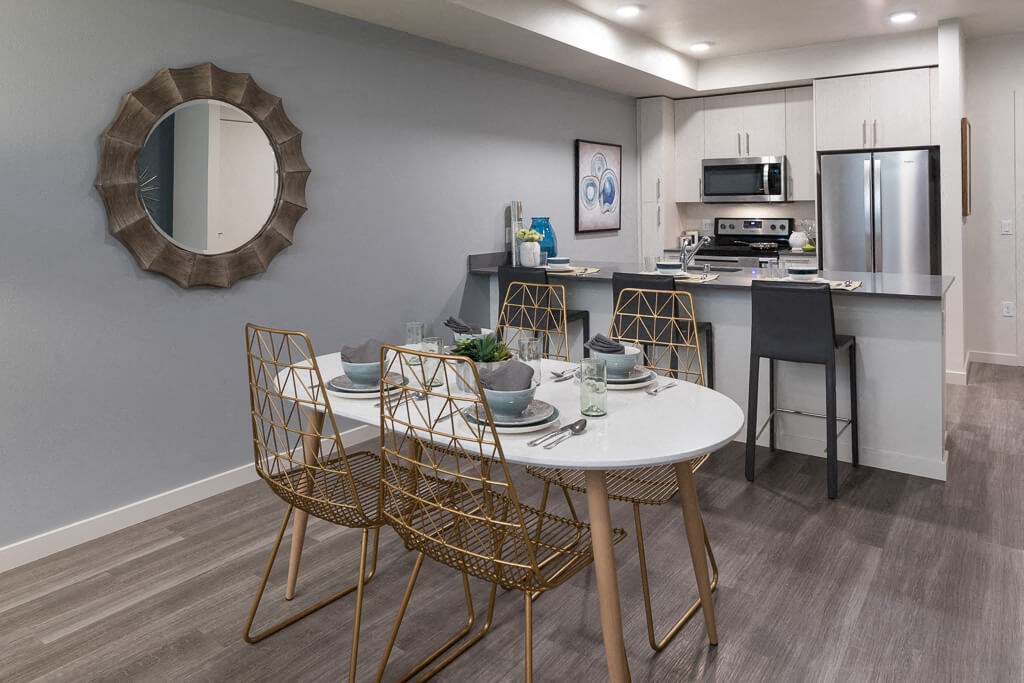 A modern dining area with a round mirror and a white table. at Ravello Apartments, Redmond, WA, 98052