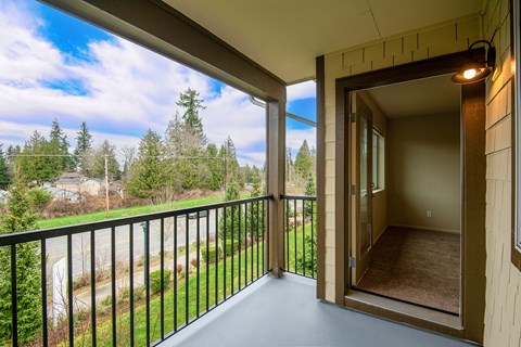 Covered balcony with black railing and entry door at Mill Creek Meadows Apartments, Mill Creek, WA 98012