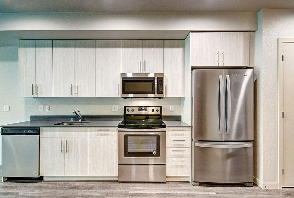 A modern kitchen with stainless steel appliances and white cabinets. at Ravello Apartments, Redmond, WA