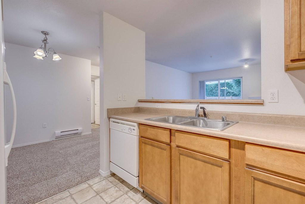 A kitchen with a white dishwasher and wooden cabinets at Valley Springs Apartments, Renton, WA
