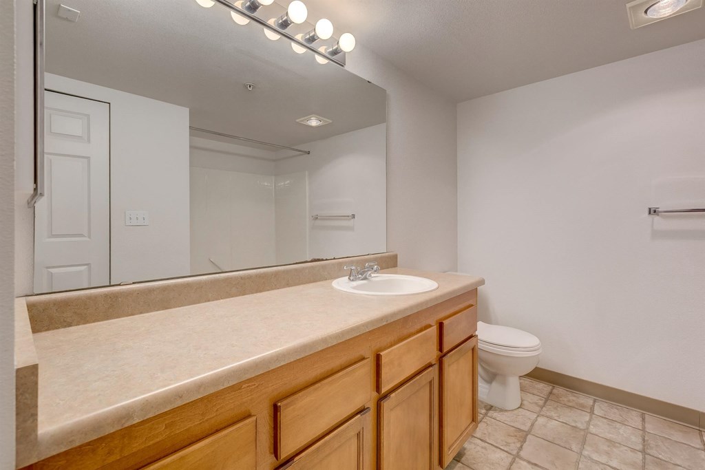 A bathroom with a sink, mirror, and toilet at Valley Springs Apartments, Renton, WA