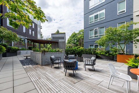 A patio with a table and chairs is surrounded by buildings. at Kirkland Crossing Apartments, Kirkland, Washington