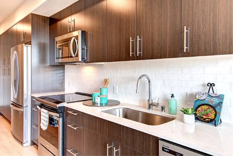 A modern kitchen with a stainless steel refrigerator and wooden cabinets.