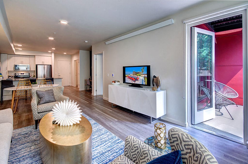 A modern living room with a white sofa and a TV on a white stand. at Ravello Apartments, Redmond, WA