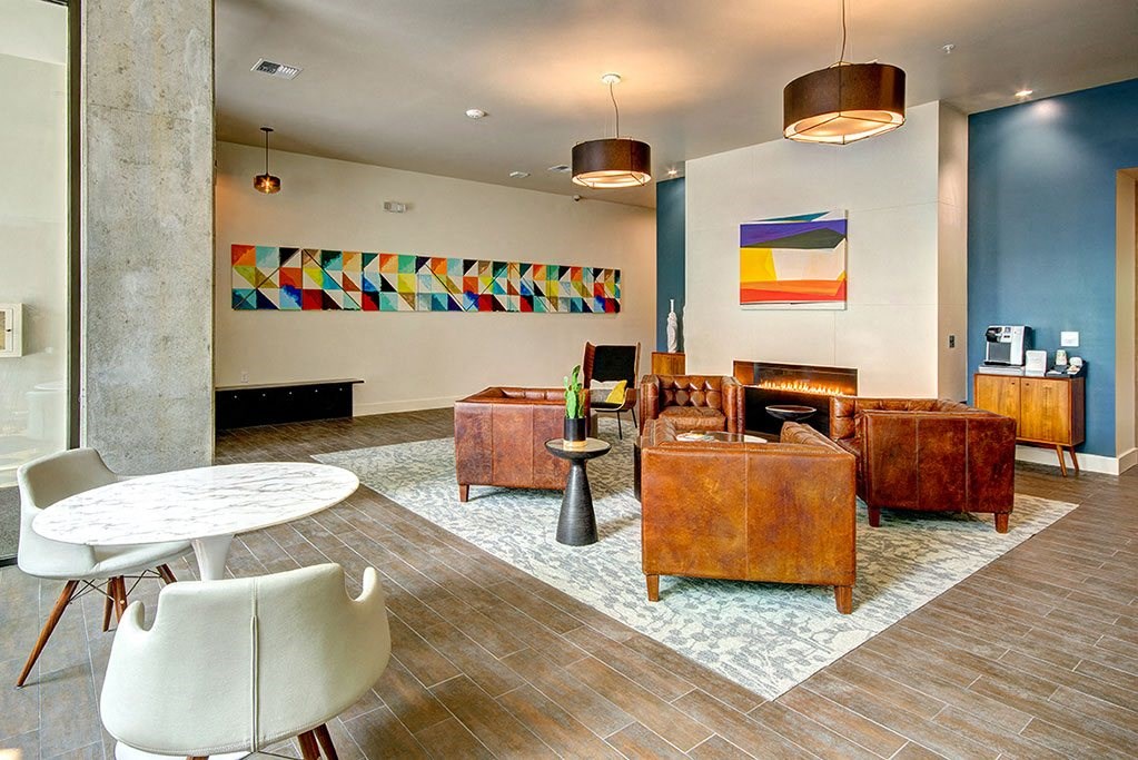 A living room with a white chair and a brown leather couch. at Ravello Apartments, Redmond