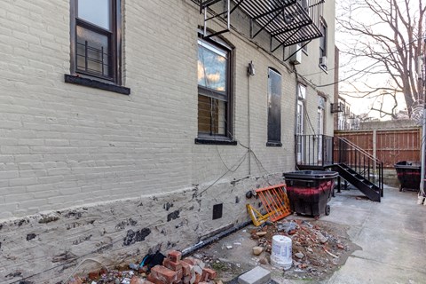 A white building with a black window and a black railing.