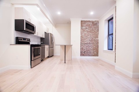 A kitchen with a brick wall and wooden floors.