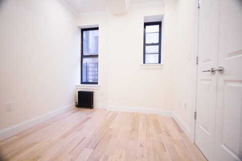 A room with wooden floors and two windows.