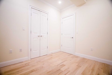 A room with two white doors and wooden floors.