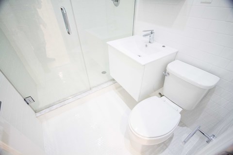 A white toilet sits next to a white sink in a bathroom.
