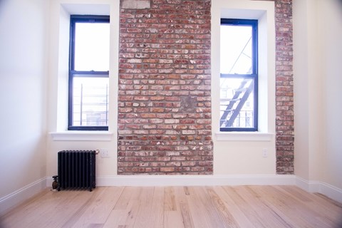 A room with a brick wall and two windows.