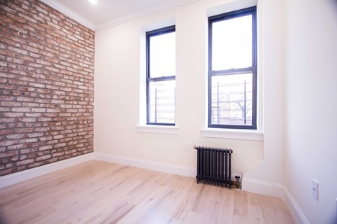 A room with a brick wall and a wood floor.