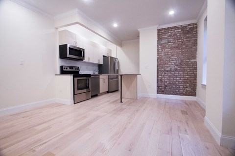 A kitchen with a brick wall and wooden floors.
