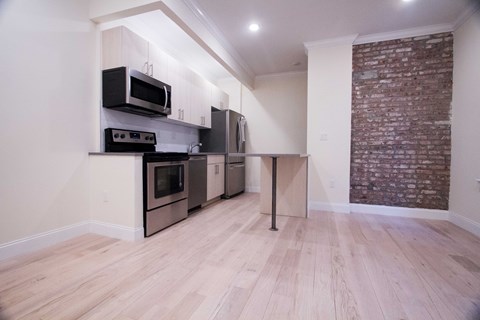 A kitchen with wooden floors and a brick wall.