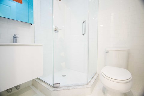 A white toilet sits next to a glass shower stall in a bathroom.