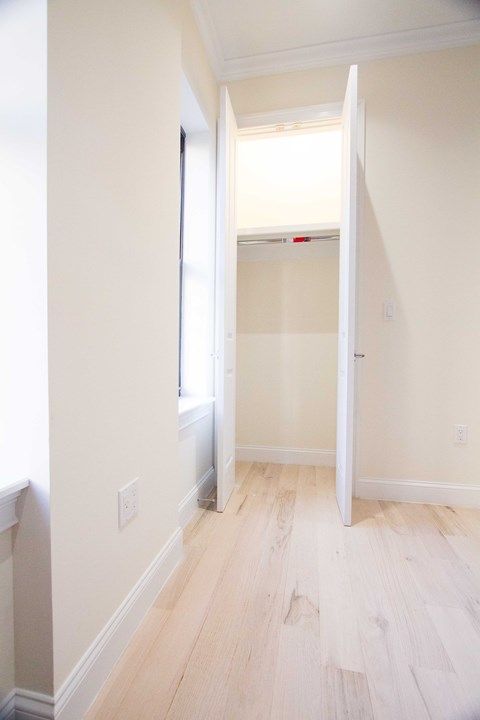 A white door is open to a room with wood flooring.