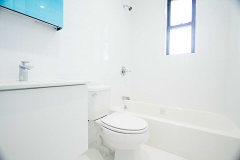 A white toilet sits next to a white bathtub in a bathroom.