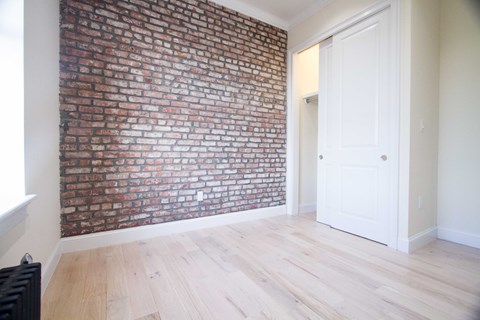 A room with a brick wall and a white door.