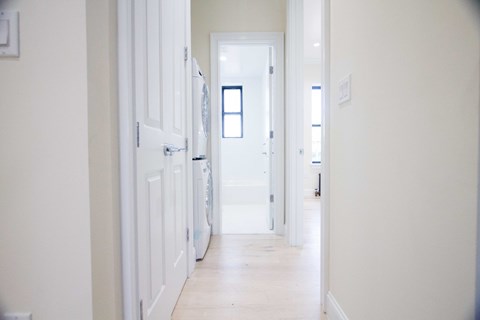 A long white hallway with a door at the end.