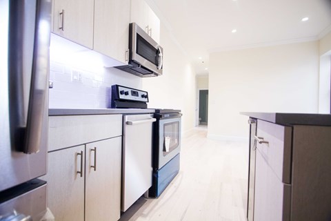 A kitchen with white cabinets and black appliances.