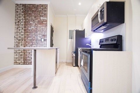 A kitchen with a brick wall and a white counter.