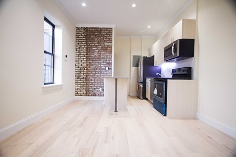 A kitchen with a brick wall and wooden floors.