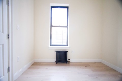 A room with a window and a radiator on the floor.
