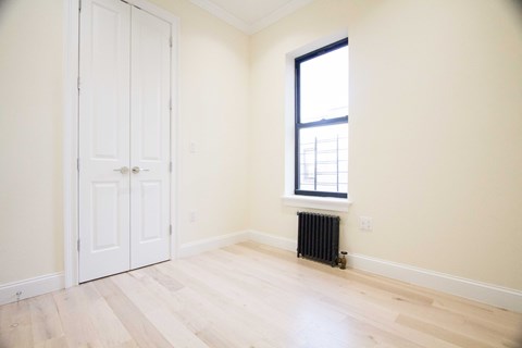 A room with a white door, a window, and a radiator.