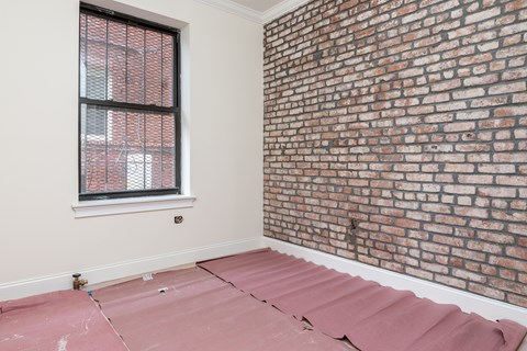 A room with a brick wall and a window with blinds.