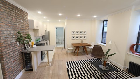 A living room with a brick wall and a black and white rug.