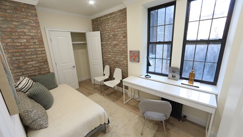 A bedroom with a bed, desk, and chair.