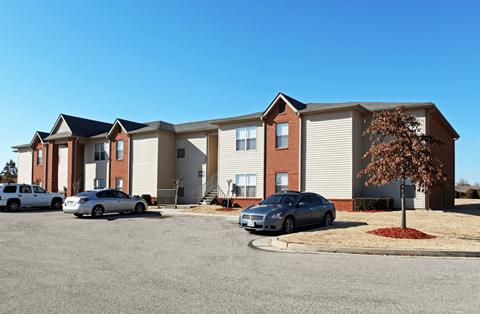 A grey building with a red brick chimney and a tree in front of it.