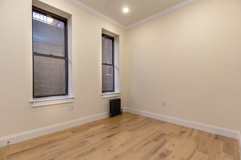 A room with wooden floors and two windows.