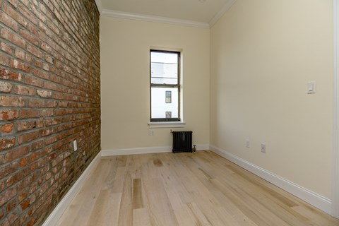 A room with a brick wall and wooden flooring.