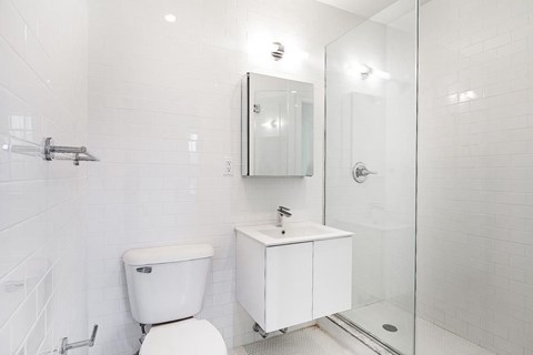 A white toilet sits next to a white cabinet in a tiled bathroom.