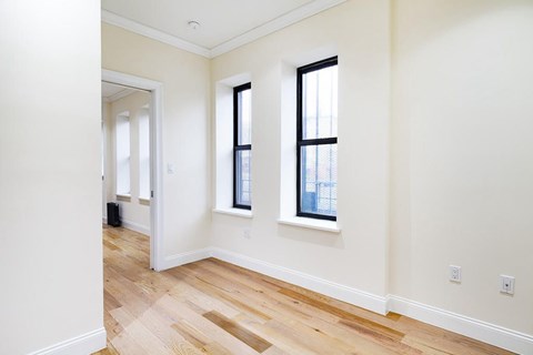 A room with wooden floors and two windows.