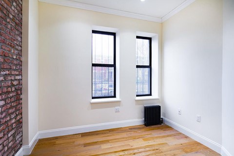 A room with a brick wall and two windows.