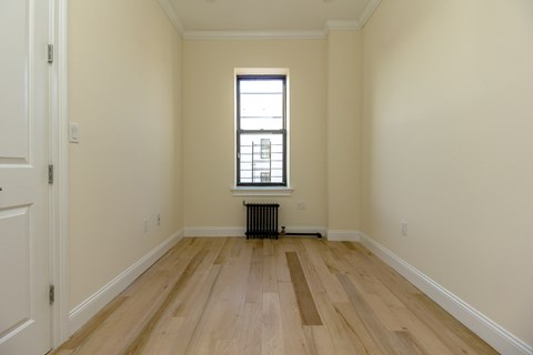 A room with a window and radiator on the floor.