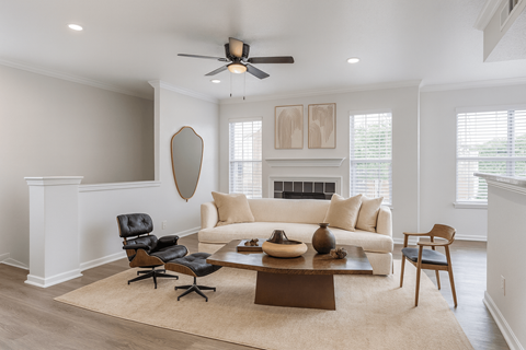 A living room with a white couch, a black chair, a brown coffee table, and a fireplace.