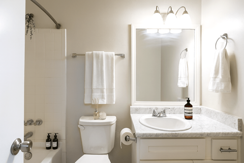 A white bathroom with a toilet, sink, and mirror.